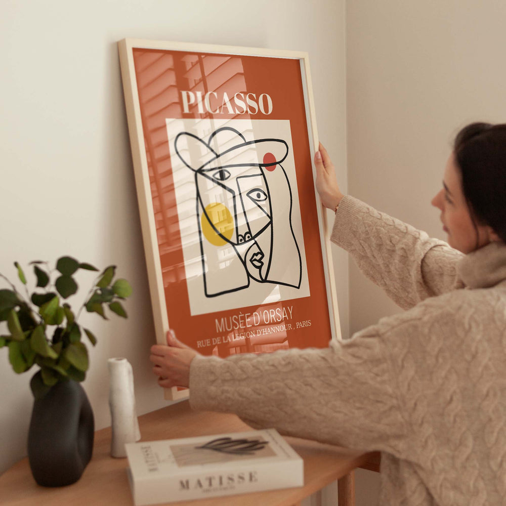 Person hanging a Picasso poster on a wall