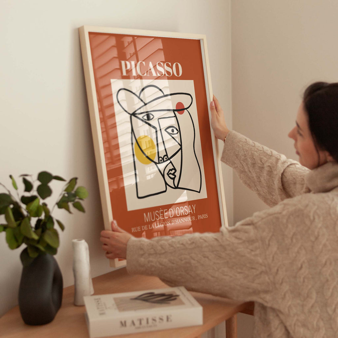 Person hanging a Picasso poster on a wall